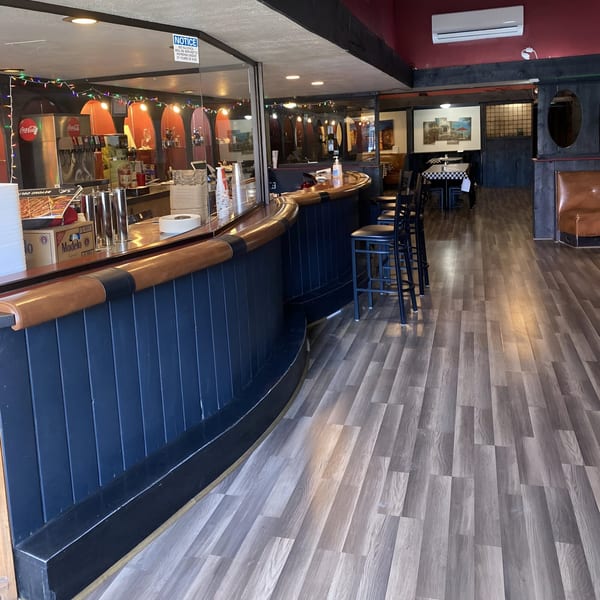 Interior view of MOMO HOUSE AND GRILL, showing the bar area with stools and dining tables.