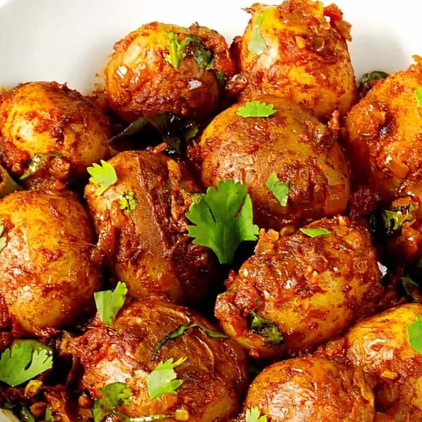Close-up of Indian-style roasted potatoes with a rich, spicy sauce and fresh cilantro.