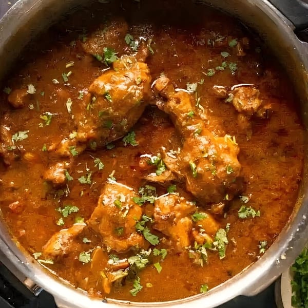Indian chicken curry with drumsticks and cilantro in a pot at MOMO HOUSE AND GRILL.