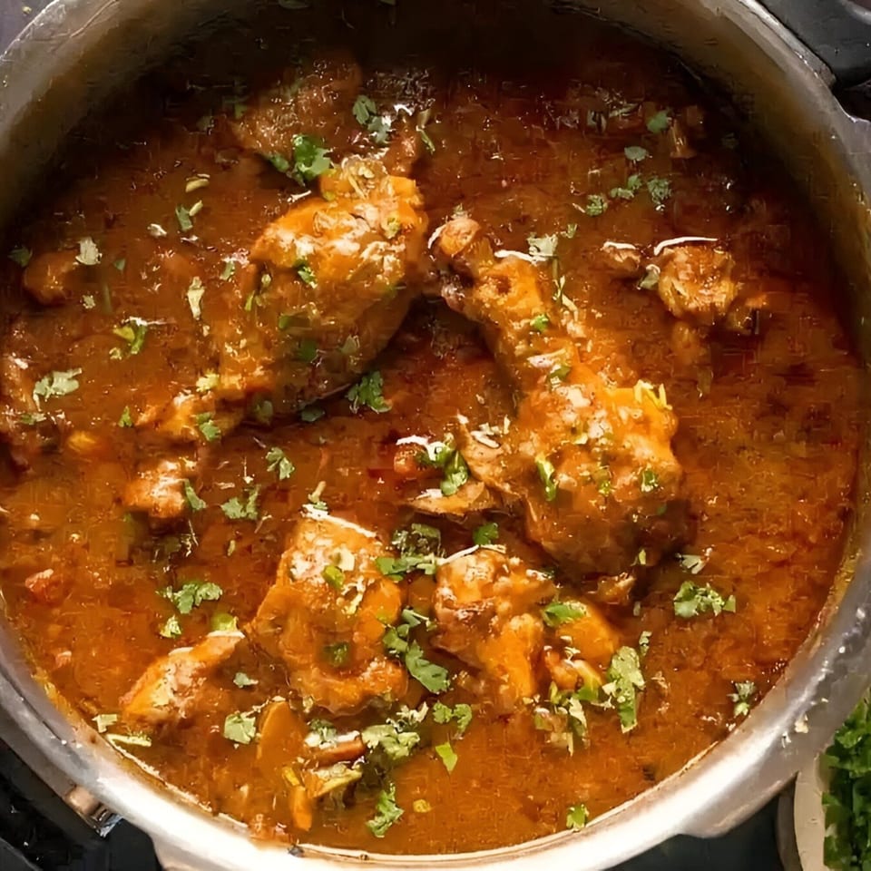 Indian chicken curry with drumsticks and cilantro in a pot at MOMO HOUSE AND GRILL.