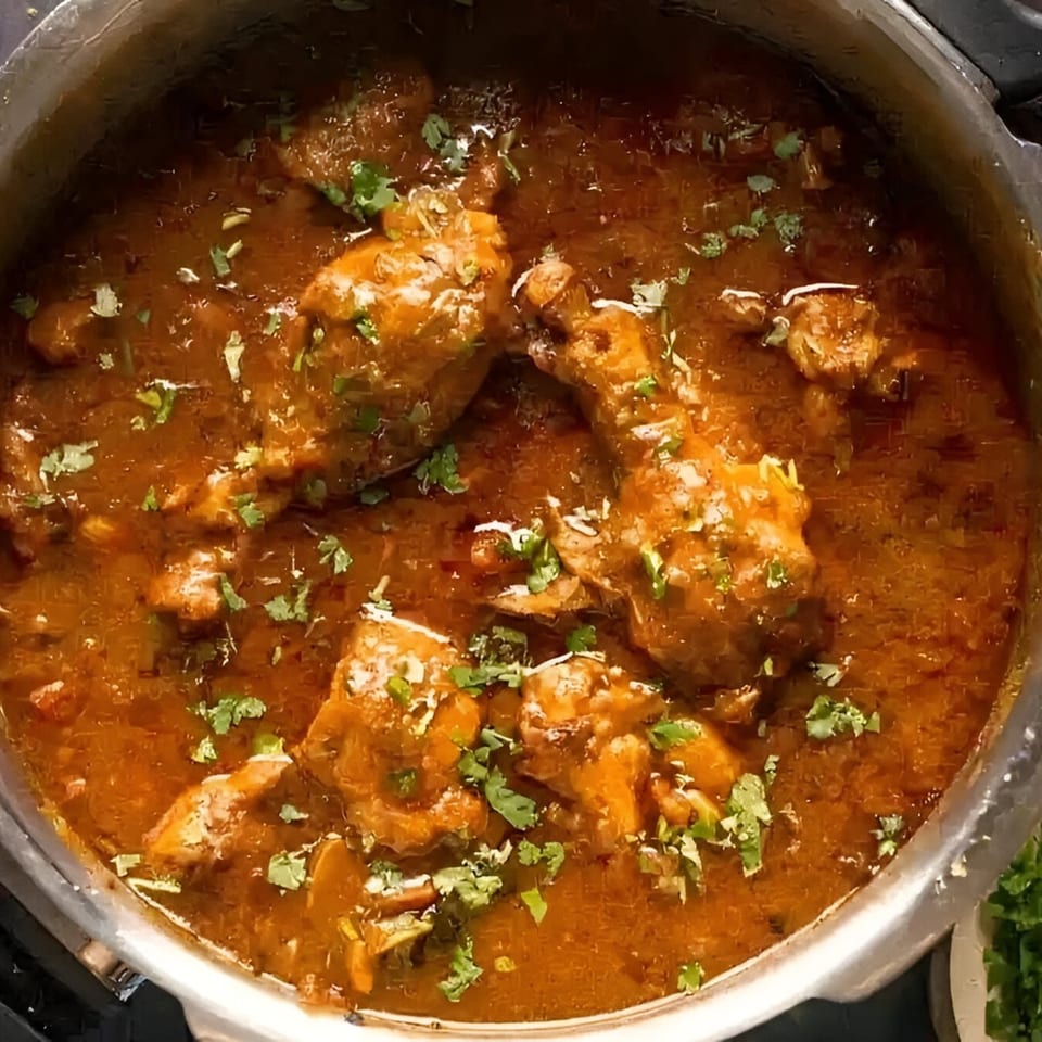 Indian chicken curry with drumsticks and cilantro in a pot at MOMO HOUSE AND GRILL.